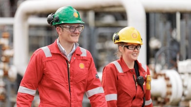 Two industrial workers in safety gear walking at a carbon capture and storage project site.