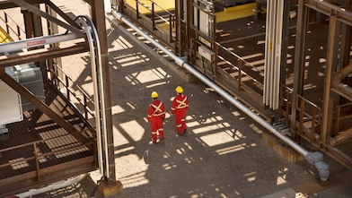 Image taken from above of two people in protective workwear walking through a processing plant