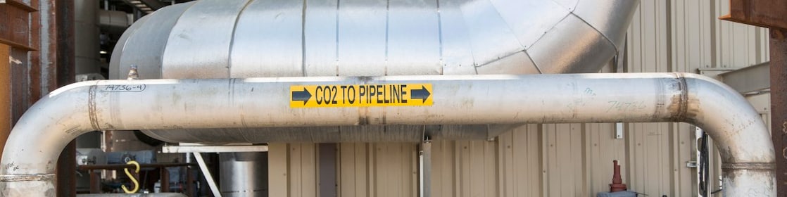 image of a pipeline transporting CO2 from for safe and permanent underground storage. The pipeline has a sticker on it indicating the direction of flow of CO2.