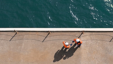Overhead view of technicians in full PPE shaking hands near water