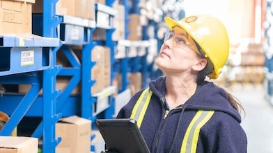 Engineer in a warehouse using a blockchain powered app to manage stock