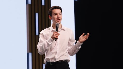 a man holding a microphone, speaking