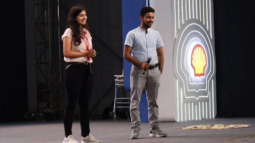 a woman and a man standing at a stage, Shell logo in the background