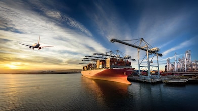 A composite image showing an airplane flying over water at sunset, a large cargo ship docked at a container port, and an industrial refinery complex on the right.