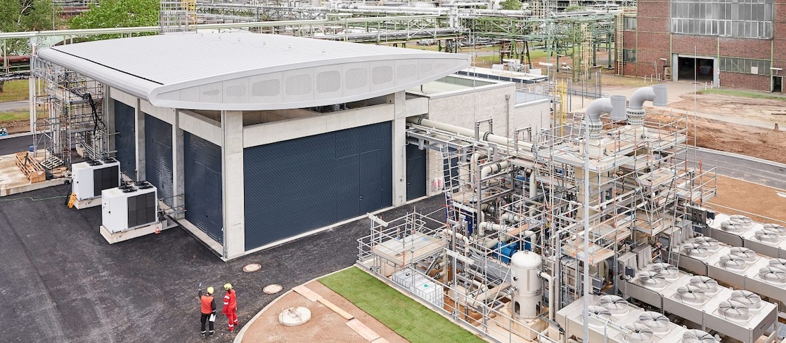 Shell hydrogen production facility in a desert landscape, with storage tanks, industrial buildings and surrounding road infrastructure.