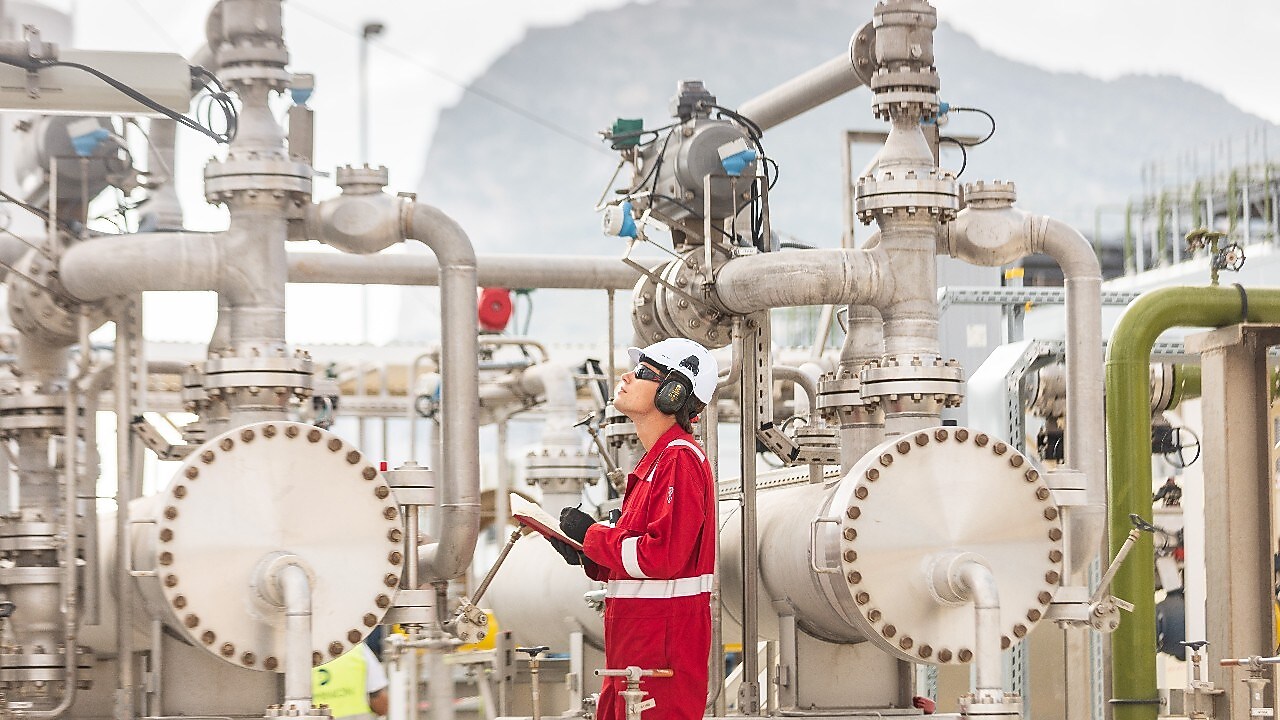 man on a LNG plant holding a notebook