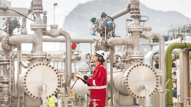 man on a LNG plant holding a notebook