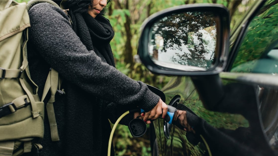 A person plugs a charge cable into an electric vehicle