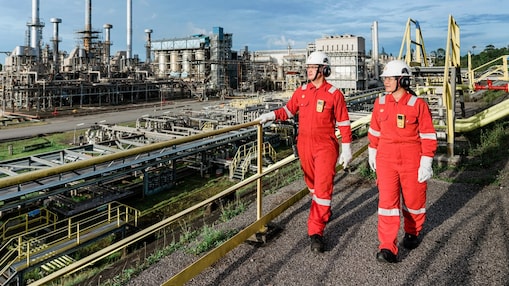 Two people in red protective coveralls walking through Shell MDS GTL facility in Bintulu, Malaysia.