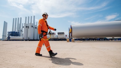 A man walking next to a wind turbine construction site