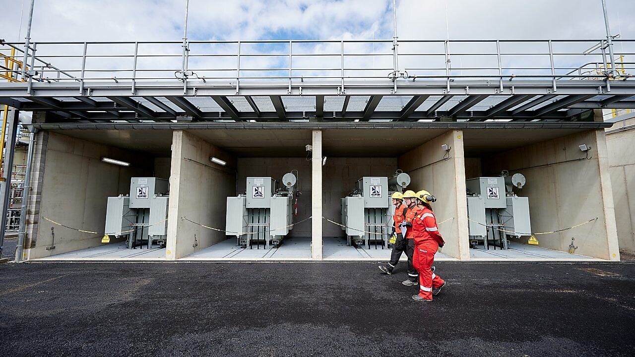 Staff walk past rectifier transformers at the plant