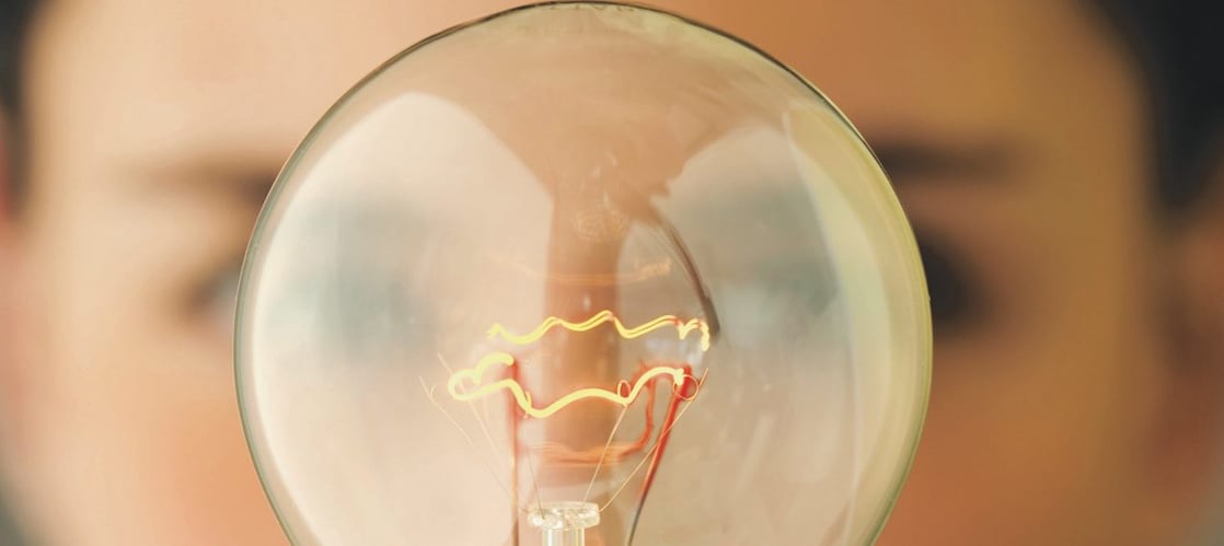 Woman holding light bulb in front of face