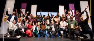 A group of people stands on stage at a Demo Day event.