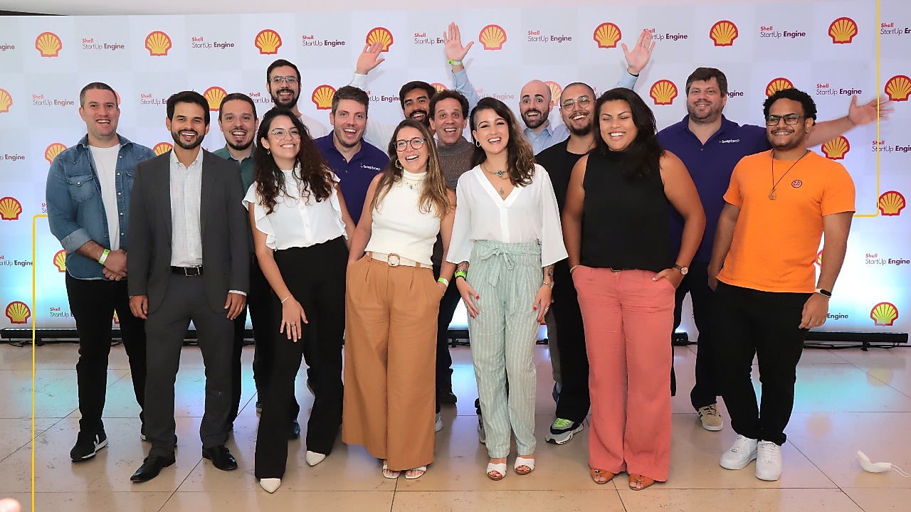 Thirteen people are posing for a group photo in front of a backdrop featuring the Shell logo and "Shell StartUp Engine" text.