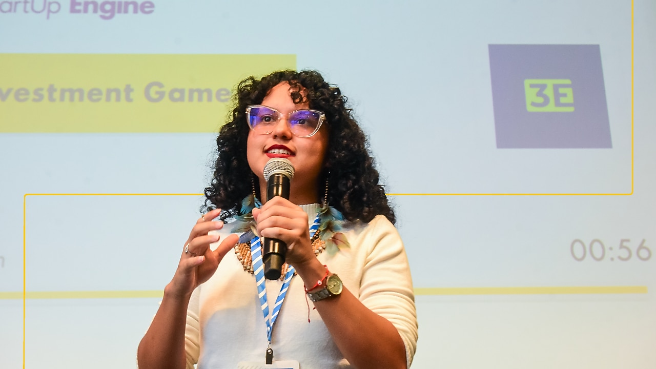 A presenter speaks at the SSE 2024 Brazil Investment Game, gesturing in front of a slide.