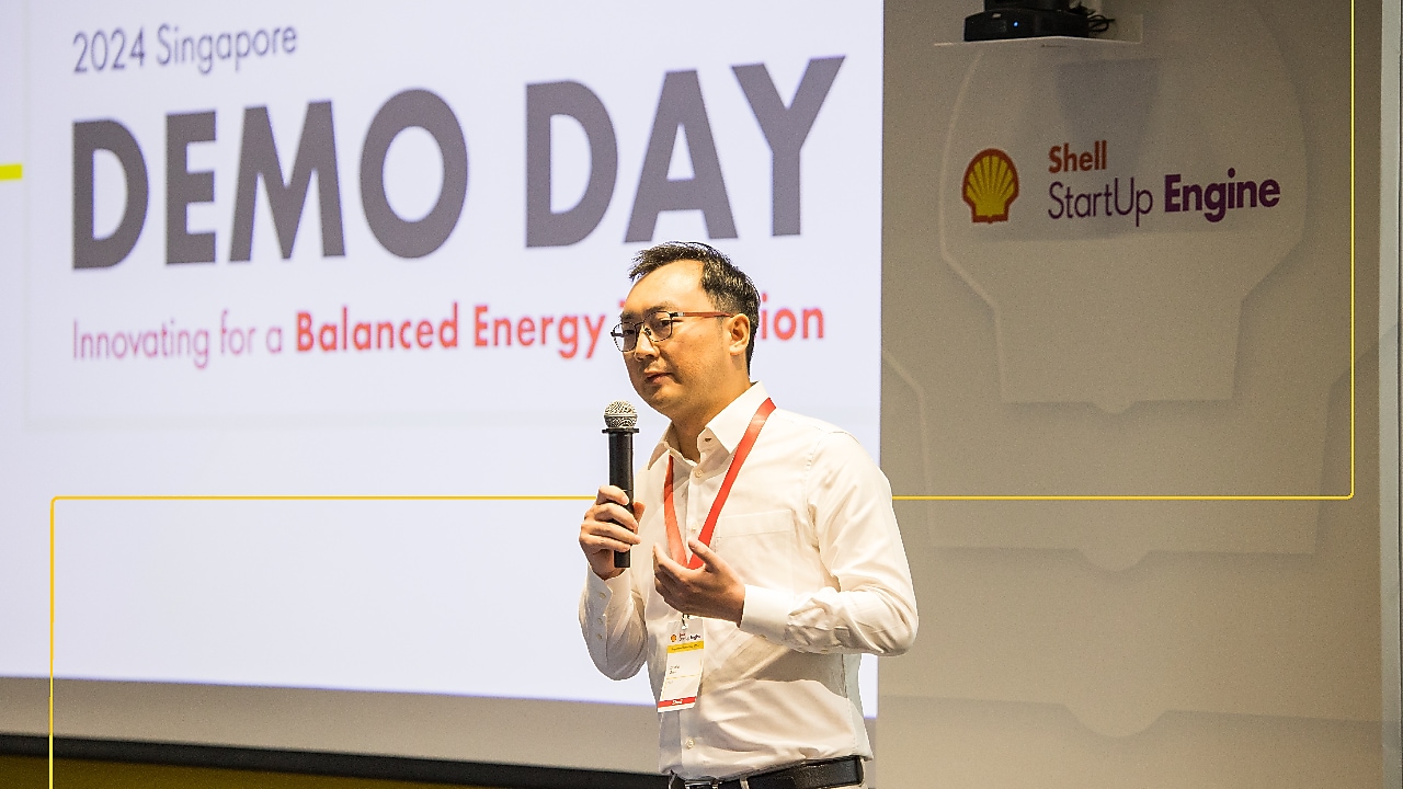 A presenter speaks at the SSE 2024 Singapore Demo Day, gesturing in front of a slide displaying the title '2024 Singapore Demo Day - Innovating for a Balanced Energy Transition.'