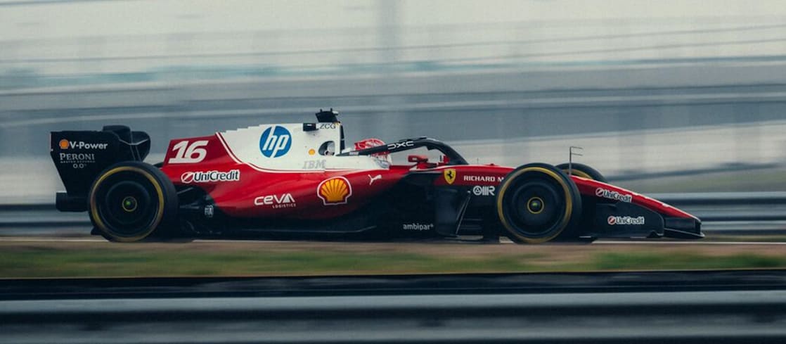 A Scuderia Ferrari HP Formula 1 car speeds along the Fiorano test track, captured in motion with blurred surroundings.