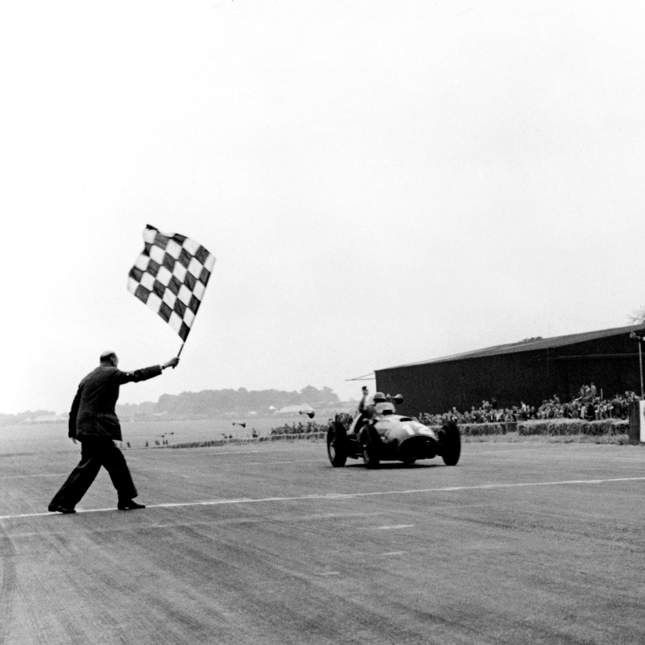 José Froilán González driving a Ferrari 375 F1 across the finish line at the 1951 British Formula 1 Grand Prix at Silverstone.