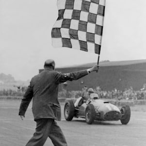 José Froilán González driving a Ferrari 375 F1 across the finish line at the 1951 British Formula 1 Grand Prix at Silverstone. 
