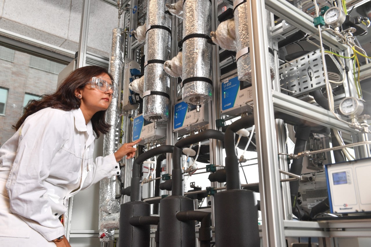 A woman in white coat in a laboratory looking at the equipment behind DAC technology