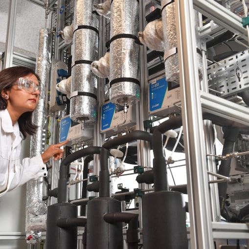 A woman in white coat in a laboratory looking at the equipment behind DAC technology