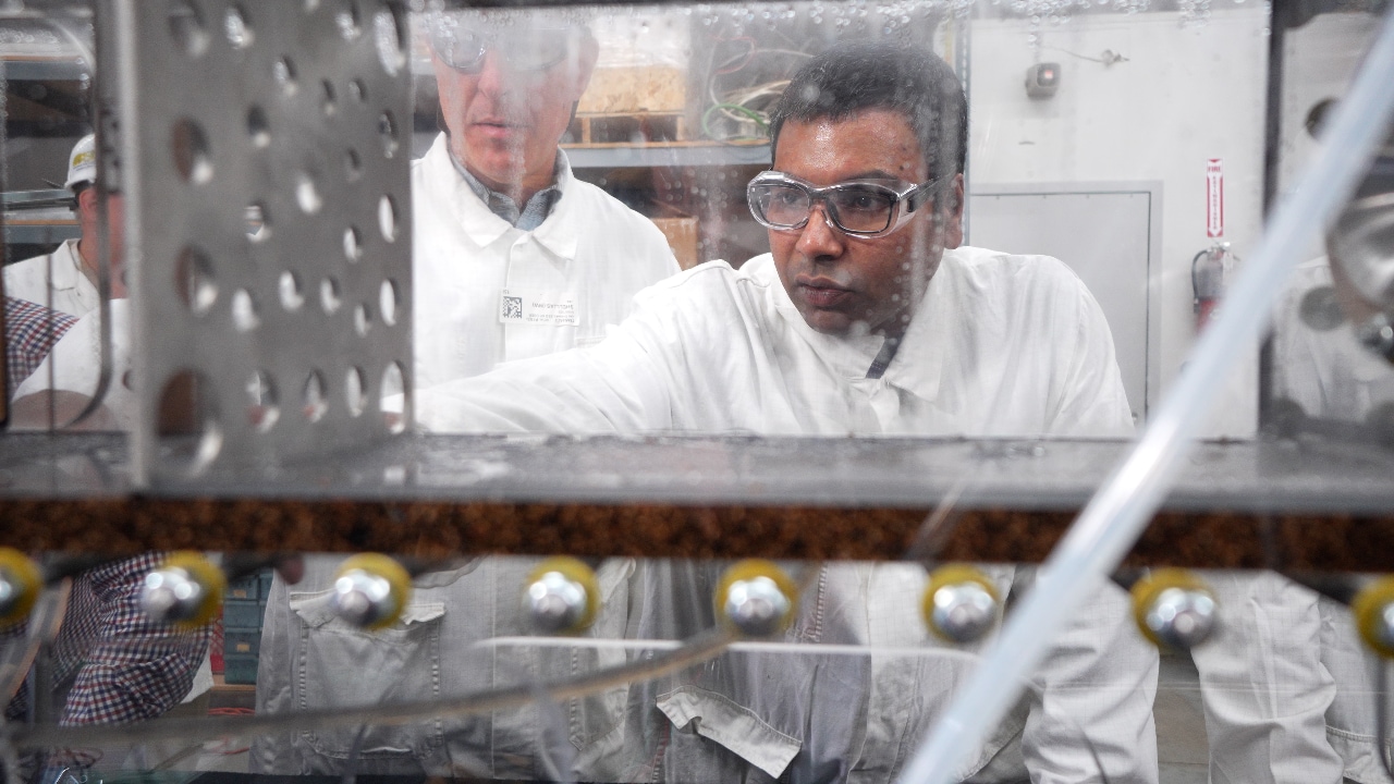 A group of people in white coats watching machinery close