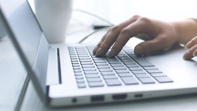 silver laptop with hands typing on it