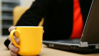 Man on the laptop holding a cup