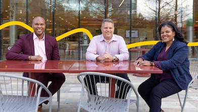 Three people sitting in an open space