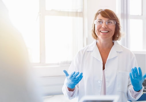 Woman in white lab coat wearing protective glasses