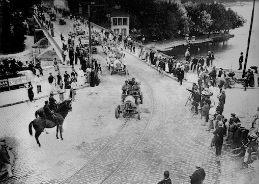 Black and white photo of people lining the street at Paris motor rally